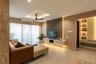 Modern minimalist living room with a neutral color palette, featuring a floating TV unit, recessed cove lighting, and a beige L-shaped sofa.